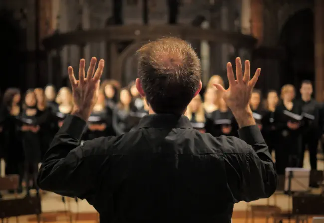 Musiker führt während eines Konzerts in einer Kathedrale einen Chor. Musikalische Proben vor dem Konzert während der Weihnachtszeit. Leben der Musiker und klassische heilige Musik.