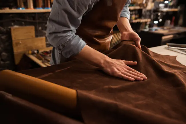 Nahaufnahme eines männlichen Schuhmachers, der in seiner Werkstatt mit Ledertextilien arbeite