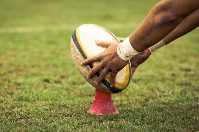 Rugby-Spieler, der sich darauf vorbereitet, während des Spiels den ovalen Ball zu treten