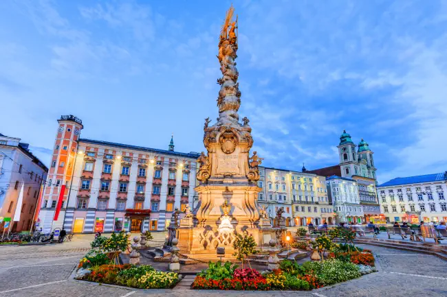 Dreifaltigkeitssäule am Linzer Hauptplatz mit schönen Blumen. Klicke hier um auf die Seite Veranstaltungen in Linz zu wechseln